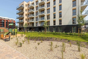 A multi-story residential building with balconies, a playground, and landscaped areas.