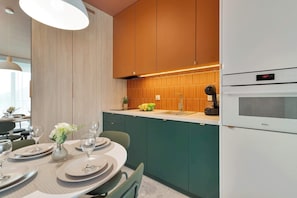 Una cucina moderna con mobili verdi, un piano di lavoro bianco e un forno integrato.