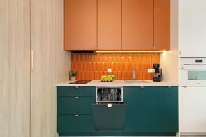 Una cucina con mobili verdi, un piano di lavoro bianco e una lavastoviglie.