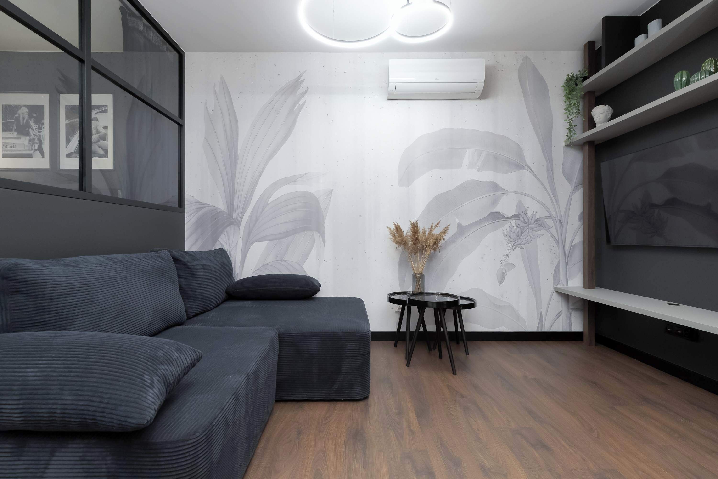 Una sala de estar moderna con un sofá modular, una mesita redonda y un televisor montado en la pared.