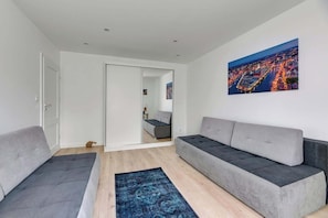 A modern living room with a sofa, a rug, and a cityscape painting. - Comfortable Apartment | Close to the Center | Pet Friendly (Gdańsk)