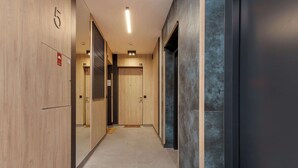 Un couloir aux murs en bois, aux portes numérotées et au sol carrelé.
