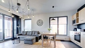 A modern kitchen with a dining table, built-in oven, and a clock on the wall.