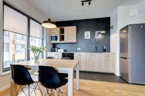 Una cocina moderna con armarios de madera, un refrigerador de acero inoxidable y un comedor con mesa y sillas.