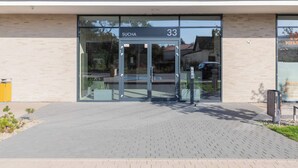 Une entrée moderne avec une porte en verre portant l’inscription « SUCHA 33 ».