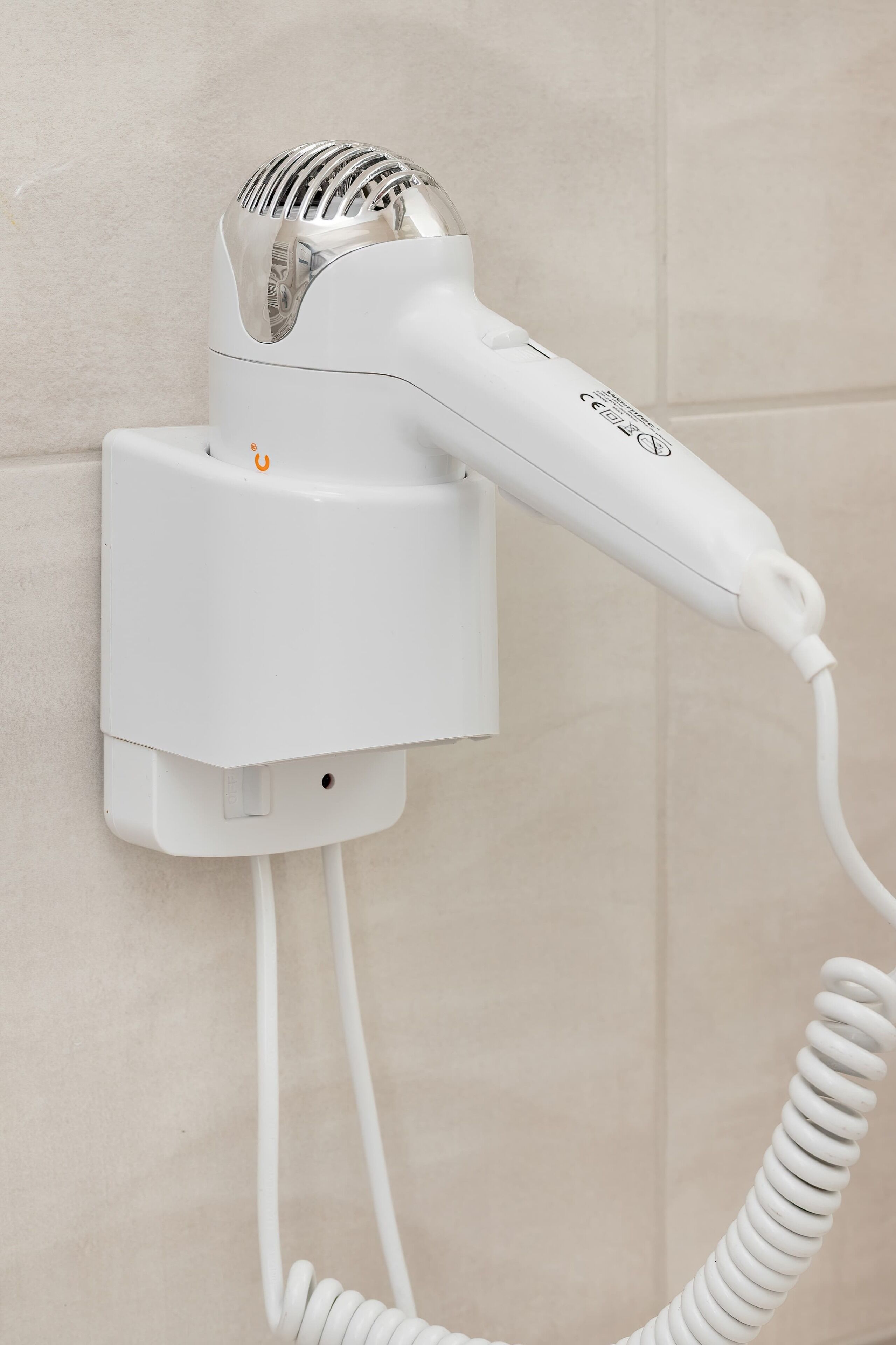 A hair dryer mounted on a wall with a cord.