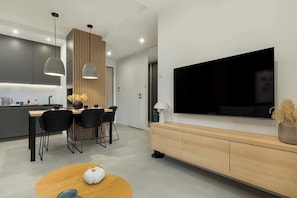 Une cuisine moderne avec des meubles de couleur sombre, un mur d’accent en bois et des luminaires suspendus.