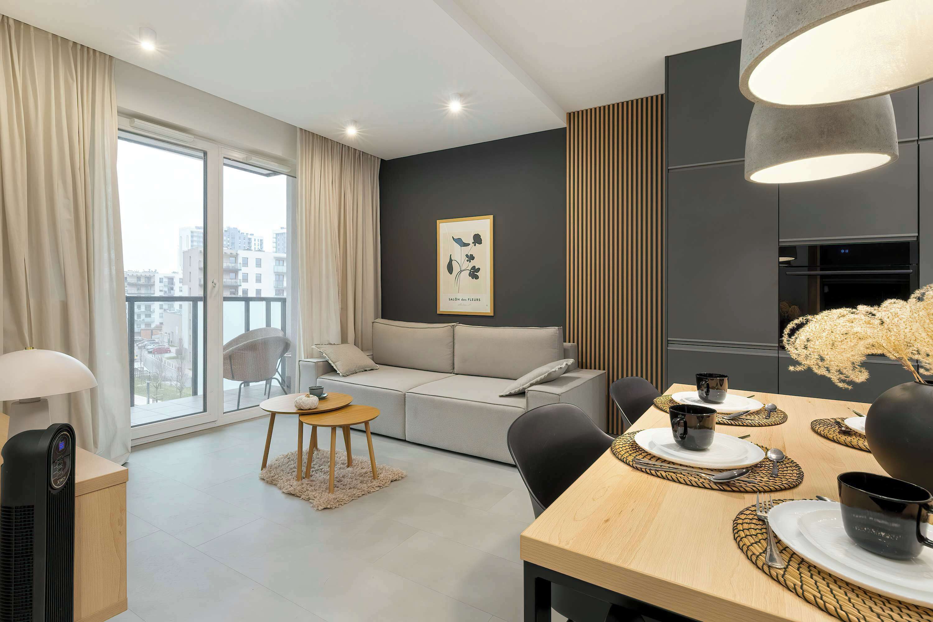 A wider view of the modern living room with access to the balcony and a dining area with a comfortable table.