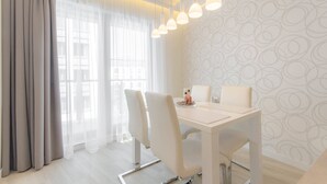 Un comedor moderno con una mesa blanca, sillas y lámparas colgantes.