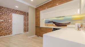 Una cocina moderna con paneles de madera, encimera blanca y un cuadro decorativo de un barco.
