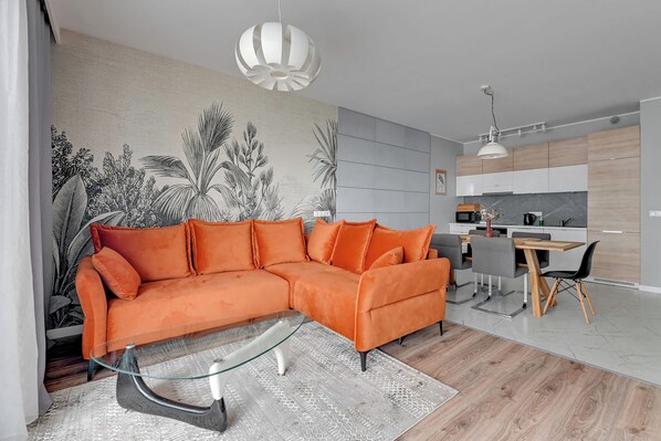A modern living room with a sectional sofa, a glass coffee table, and a dining area with a wooden table and chairs.
