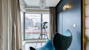 Une chambre moderne dotée d’une grande fenêtre, d’un trépied et d’un fauteuil original.