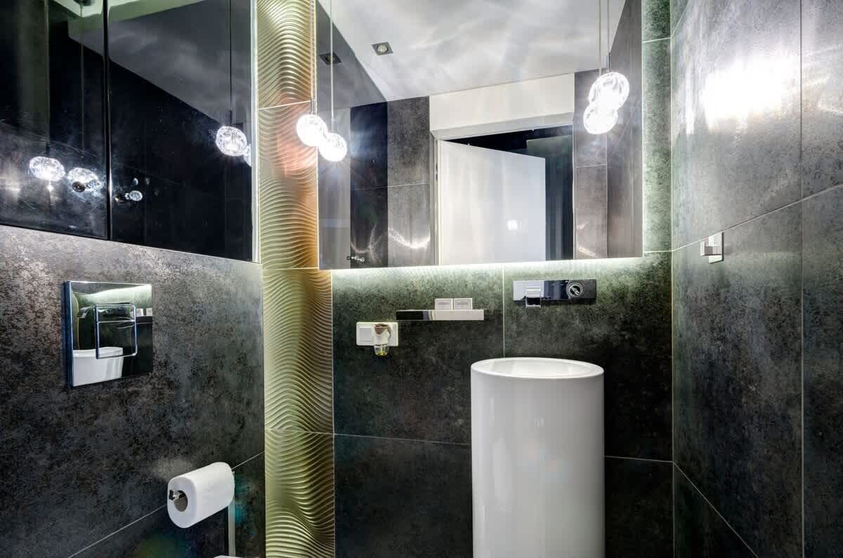 Ein modernes Badezimmer mit großem Spiegel, Toilettenpapierhalter, Waschbecken und Handtuchhalter.