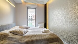 Une chambre d’hôtel avec un grand lit, une vue sur la ville par la fenêtre et un mur décoré d’un motif.