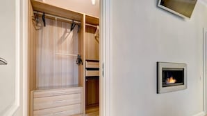 A walk-in closet with wooden doors, a built-in bench, and a wall-mounted fireplace.