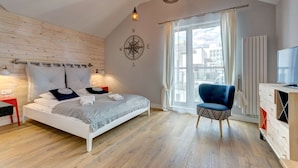 Un dormitorio con cama, una silla, un televisor, una ventana y un adorno de pared con brújula.