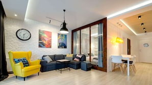 Una sala de estar moderna con sofá, sillón, mesa de comedor y obras de arte en las paredes.