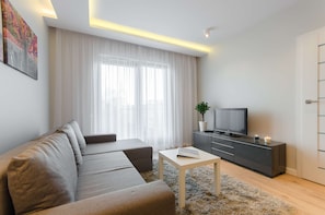 Una sala moderna con un sofá, un televisor, una mesita y un mueble de almacenamiento.