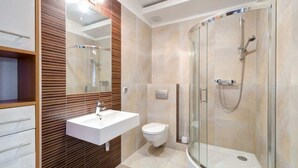 A modern bathroom with a glass-enclosed shower, a white sink, and a toilet.
