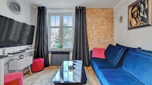 A living room with a TV, sofa, coffee table, and a window with curtains.