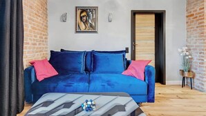 A room with a blue sofa, a coffee table with a geometric pattern, a door, and a brick wall.