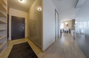 Un interior moderno con una puerta de cristal, suelo de madera, un tapete oscuro y un comedor con sillas y una mesa.