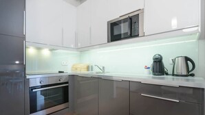 Une cuisine moderne équipée d’appareils électroménagers en acier inoxydable, d’un four à micro-ondes et d’une bouilloire posée sur le plan de travail.