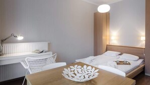 Une chambre d’hôtel comprenant un lit, un bureau avec une lampe, une chaise et une table agrémentée d’un objet décoratif.