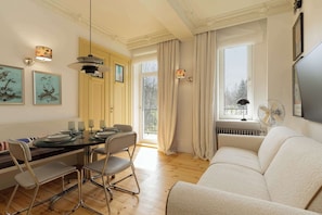 A modern living room with a sofa, dining table, chairs, and artwork on the walls.