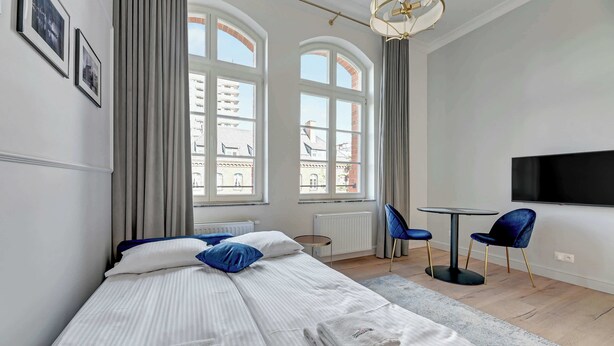 A hotel room with a bed, a TV, a small table, and two chairs. - Comfortable Studio | Gym in the Building | Close to the Old Town (Gdańsk)