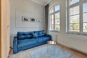 Un salon moderne avec un canapé bleu, une petite table ronde et trois tableaux encadrés accrochés au mur.