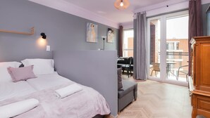 A modern bedroom with a large bed, a desk, and a view of the outside.