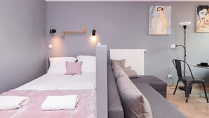 A modern bedroom with a bed, a sofa, a desk, and two wall-mounted lamps.