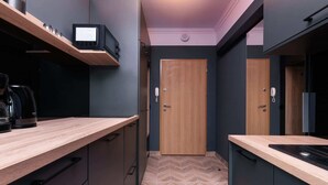 A modern kitchen with wooden countertops, a microwave, and a coffee machine.