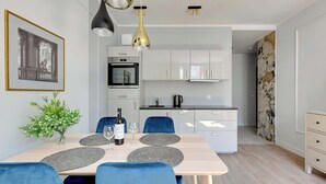 A modern kitchen with white cabinets, a built-in oven, and a coffee machine.