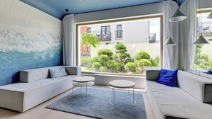A modern living room with a large window, grey sofas, and a small coffee table.