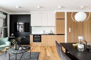 Una cucina moderna con mobili bianchi, un piano cottura nero e una parete decorativa in legno.