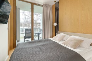 A bedroom with a large bed, a wooden headboard, and a view of the outdoors through a sliding door. - Sunny Apartment | SPA, Balcony, 300 m to the Beach (Gdańsk)