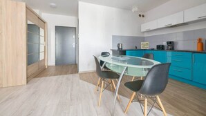 A modern kitchen with a glass dining table and chairs, a coffee machine, and a microwave.