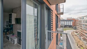 A modern apartment with a balcony, large windows, and a view of the cityscape.