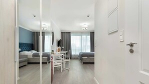 Ein modernes Hotelzimmer mit großem Spiegel, zwei Betten, einem Schreibtisch und einem Stuhl.