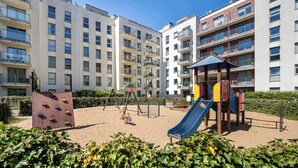 A playground with climbing walls and a slide, surrounded by apartment buildings.