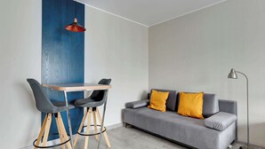 A modern living room with a grey sofa, two black chairs, a wooden table, a red pendant light, and a floor lamp.