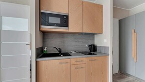 A modern kitchen with wooden cabinets, a built-in microwave, a sink, and a coffee maker.