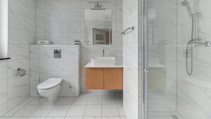 A modern bathroom with a toilet, sink, and shower.