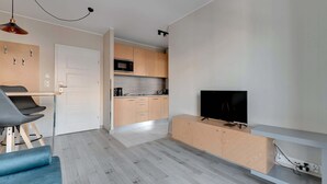 A modern kitchen with wooden cabinets, a microwave, and a TV on a stand. - Comfortable Apartment in the Center | Remote Work (Gdańsk)