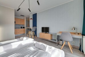 Une chambre d’hôtel moderne équipée d’un lit, d’un bureau, d’une télévision et d’une kitchenette.