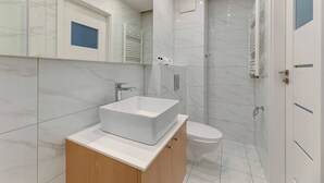 Ein modernes Badezimmer mit einem großen weißen Waschbecken, einer Toilette und einer Duschkabine.