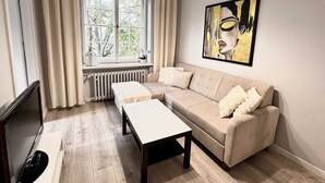 Un salon moderne avec un canapé beige, une table basse blanche et une grande fenêtre avec des rideaux.