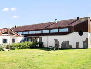 A two-story building with a sloped roof, a patio area with a table and chairs, and a grassy yard. - 9 Person Holiday Park Home in Otterup (Otterup)